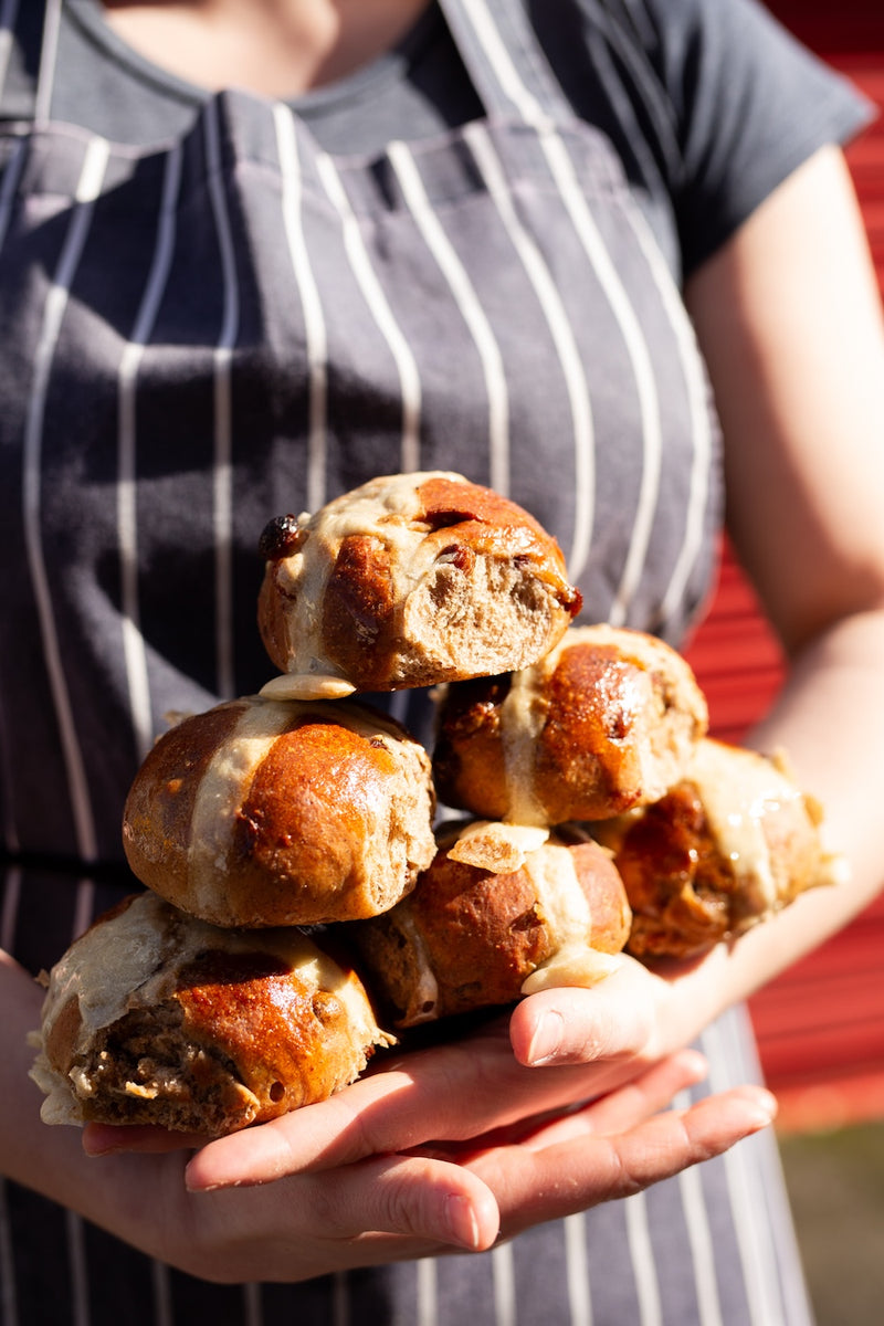 Missing bean bakery Laura holding a stack of hot cross buns with a blurred background