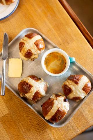 Tray with hot cross buns and a cup of coffee on a wooden table