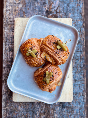 Three reuben croissants on a white plate with a wooden background
