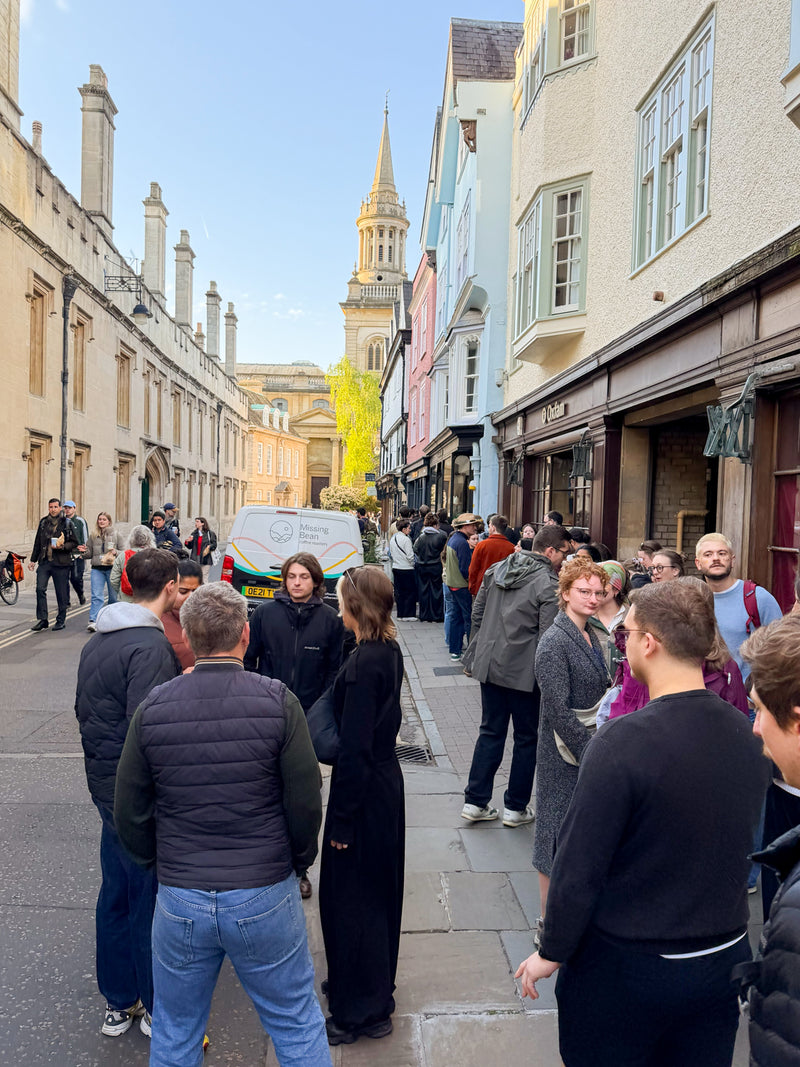 Turl Street on May Morning with a long queue leading to Missing Bean's Turl Street cafe.