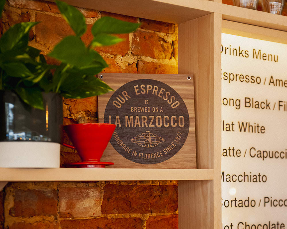 Missing Bean Banbury coffee shop detail of exposed brick wall behind shelf with V60 coffee filter and La Marzocco sign