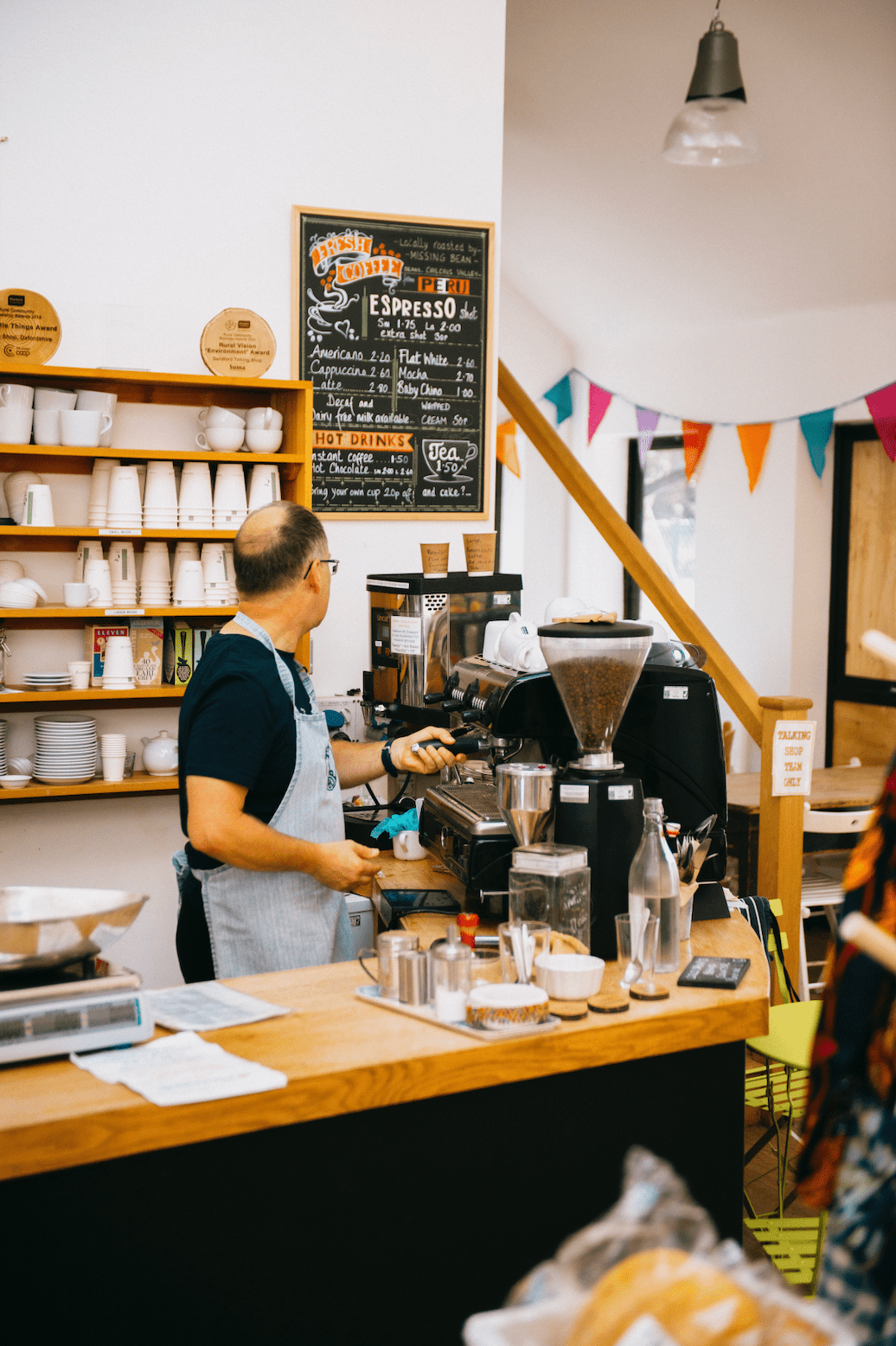 Barista on a busy coffee counter operating a coffee machine filled with Missing bean wholesale coffee beans