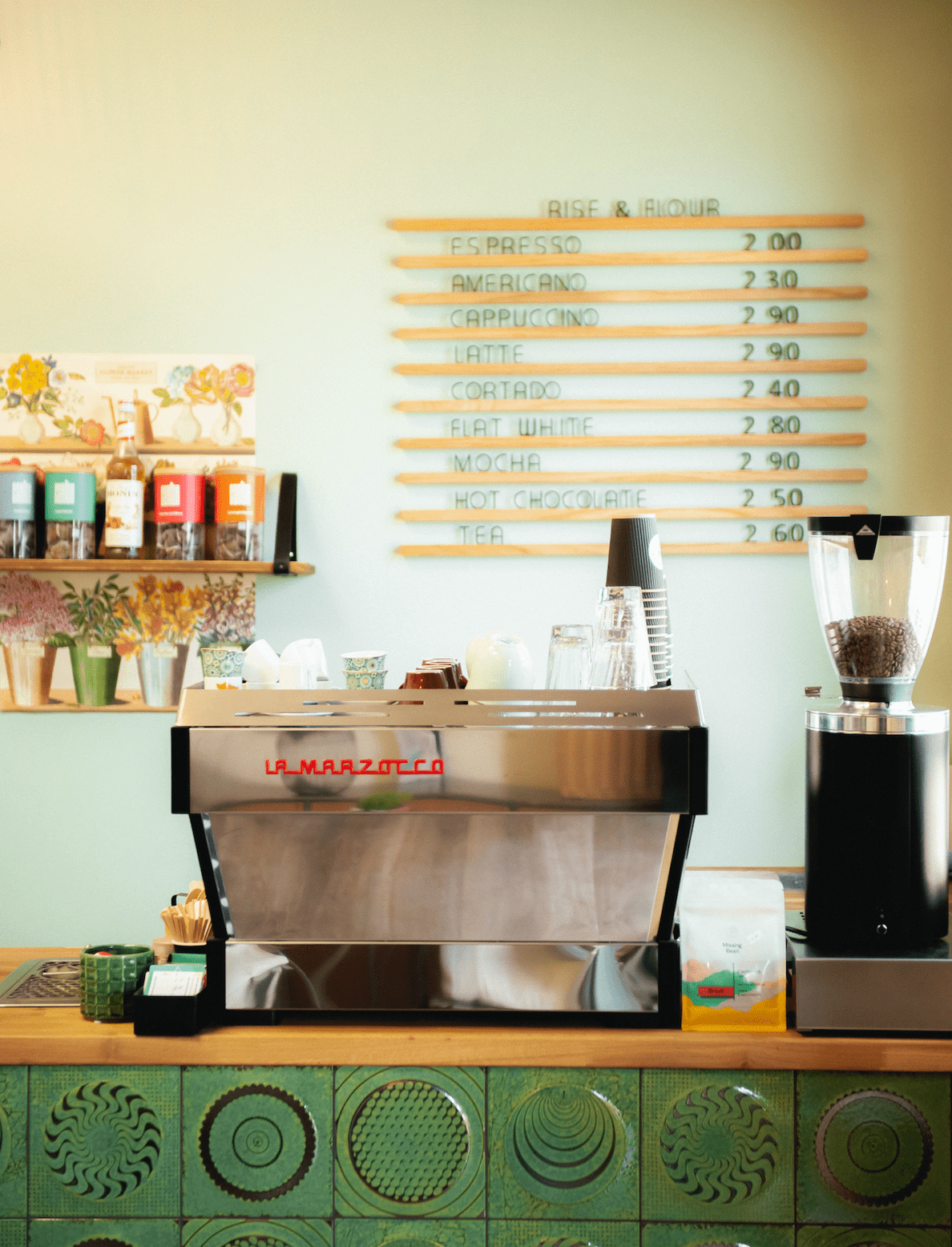 Silver La Marzocco coffee machine filled with Missing Bean wholesale coffee on a bright green tiled counter in a vibrant coffee shop