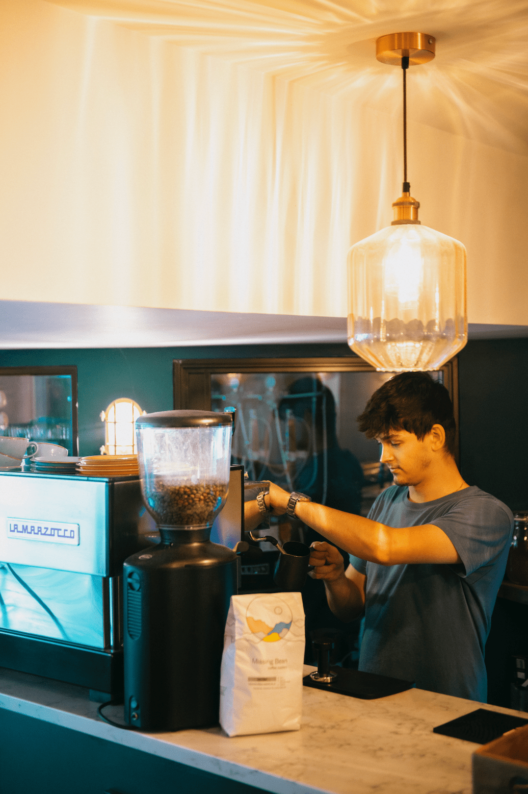 Missing Bean Coffee on a barista counter alongside a La Marzocco machine