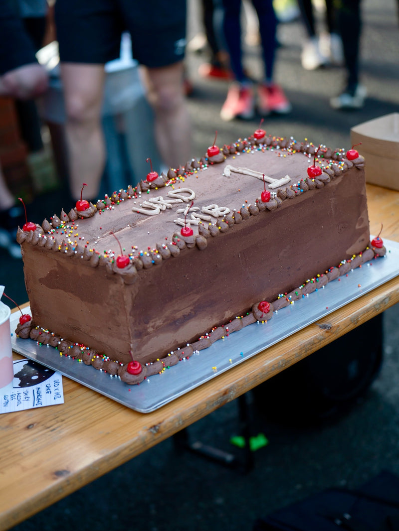 Tiramisu cake with red cherries on a wooden table, blurred people in the background