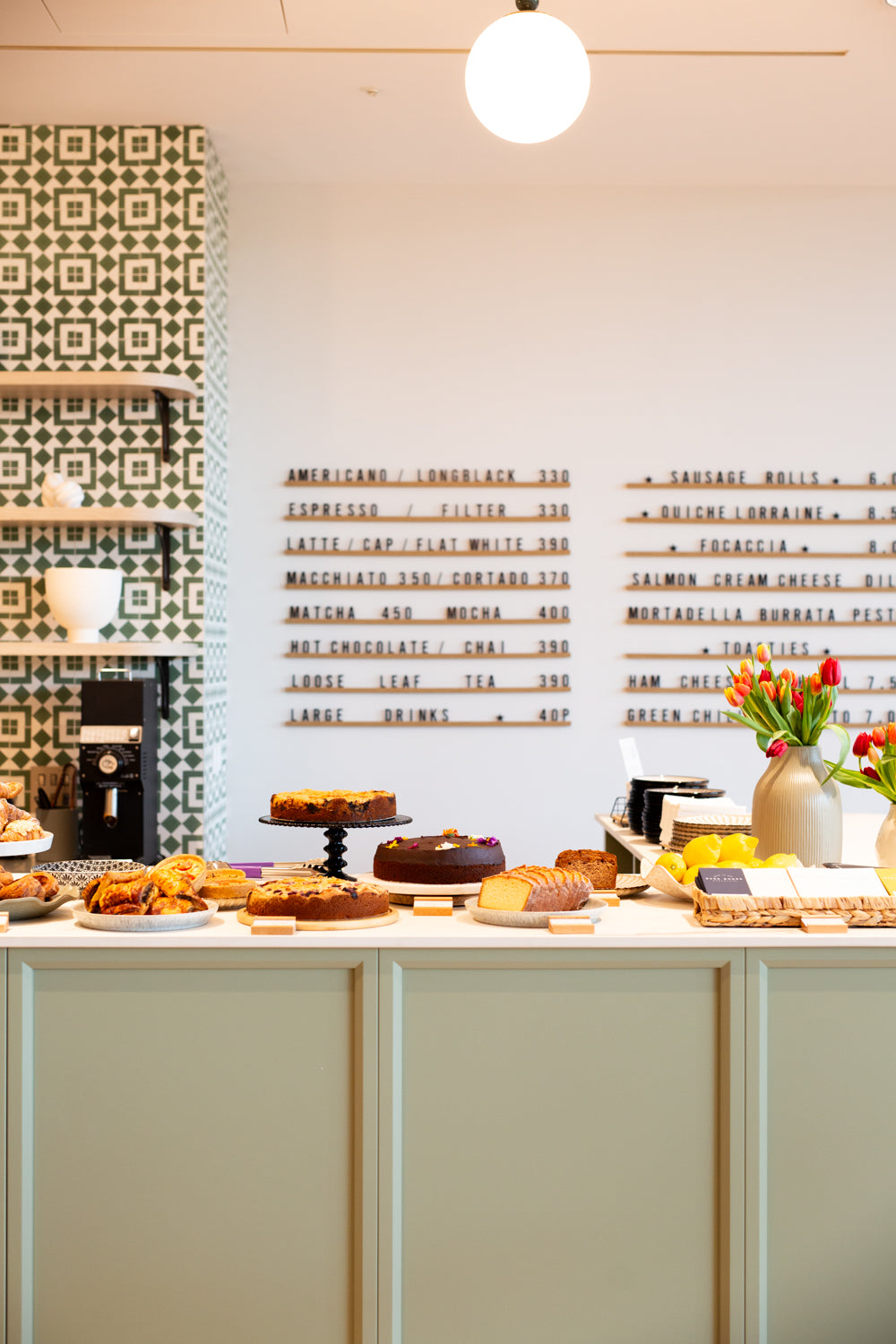 Display of pastries on a Missing Bean Cowley's counter with a decorative wall in the background