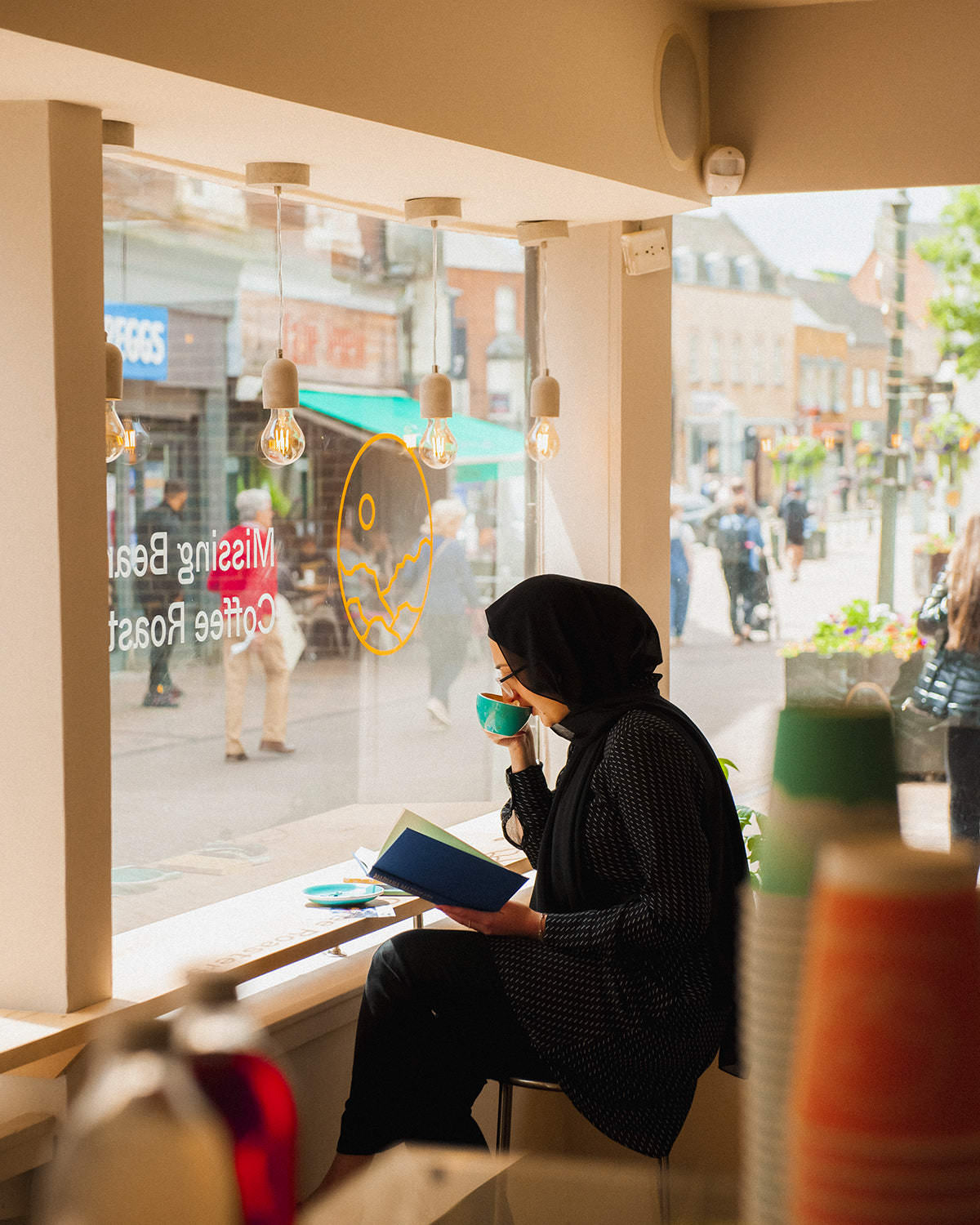 A customer enjoying a coffee and reading a book in the window of the Missing Bean cafe in Banbury