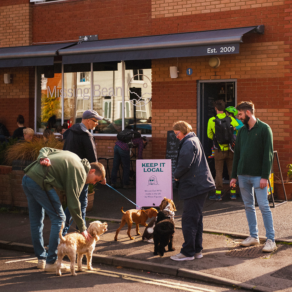 Four medium sized dogs and their owners waiting to go inside of Missing Bean's dog friendly East Oxford coffee shop and coffee bean roastery