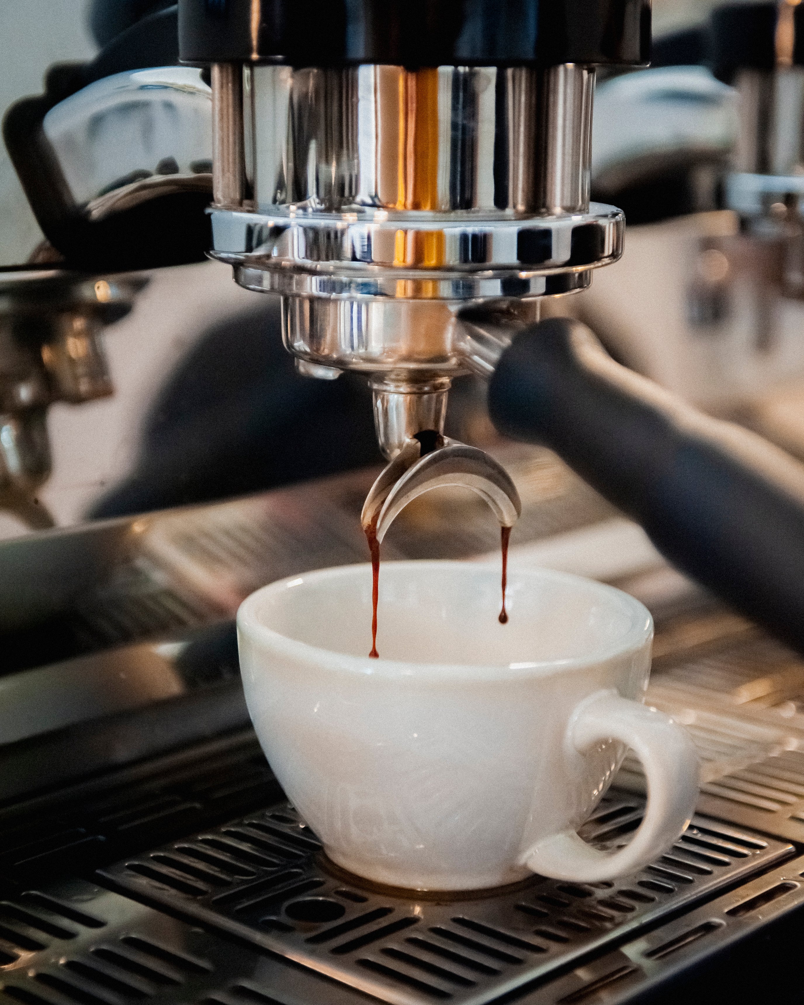 Coffee machine filling a white cup with freshly brewed coffee at a Missing bean coffee roasters cafe in Oxford.