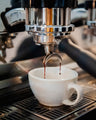 Coffee machine filling a white cup with freshly brewed coffee at a Missing bean coffee roasters cafe in Oxford.